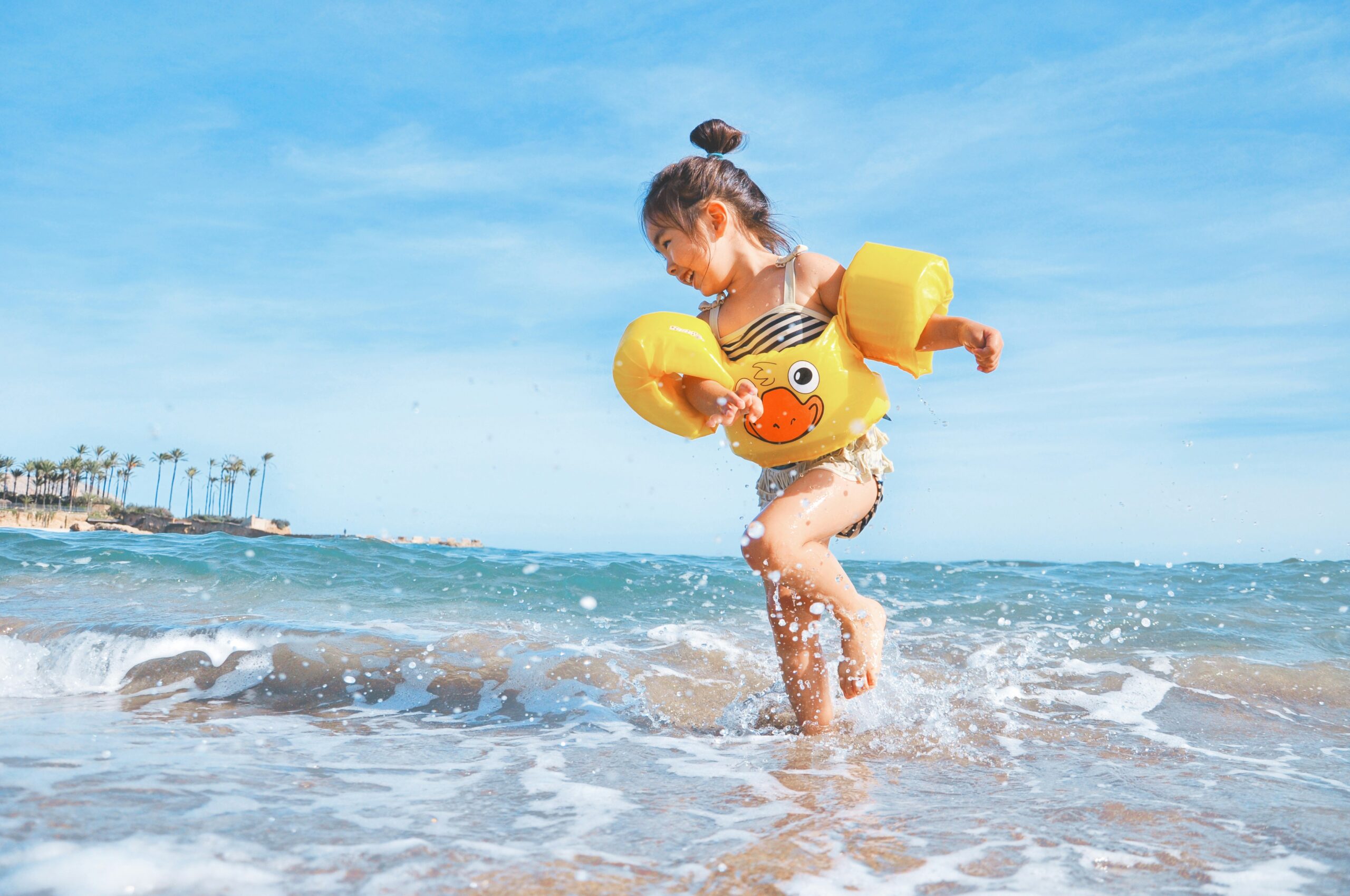 A little girl in floaties playing at the beach